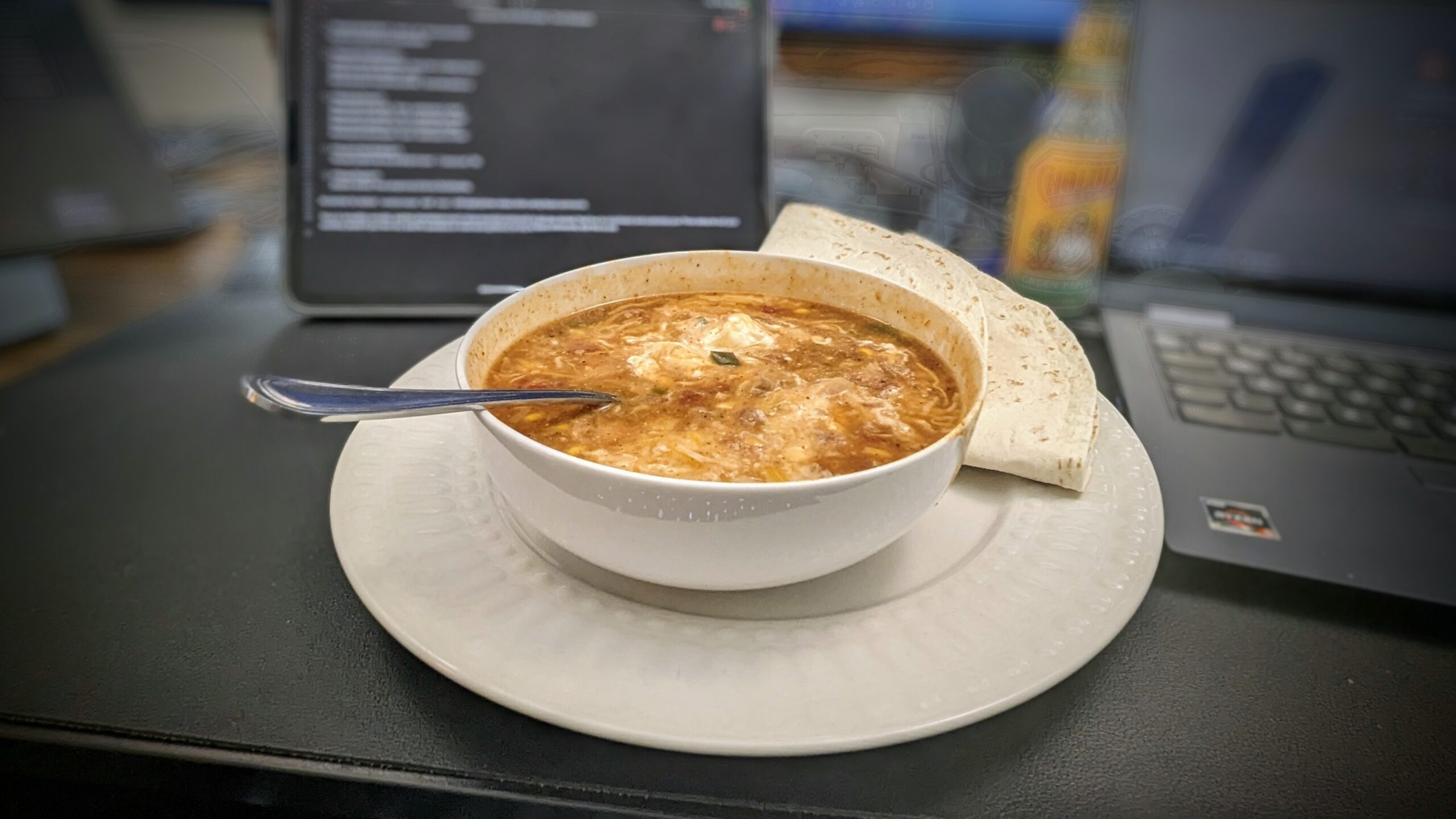 Chicken Enchilada Stew, topped with shredded Wisconsin sharp cheddar cheese and sour cream, with buttered flour tortillas on the side.